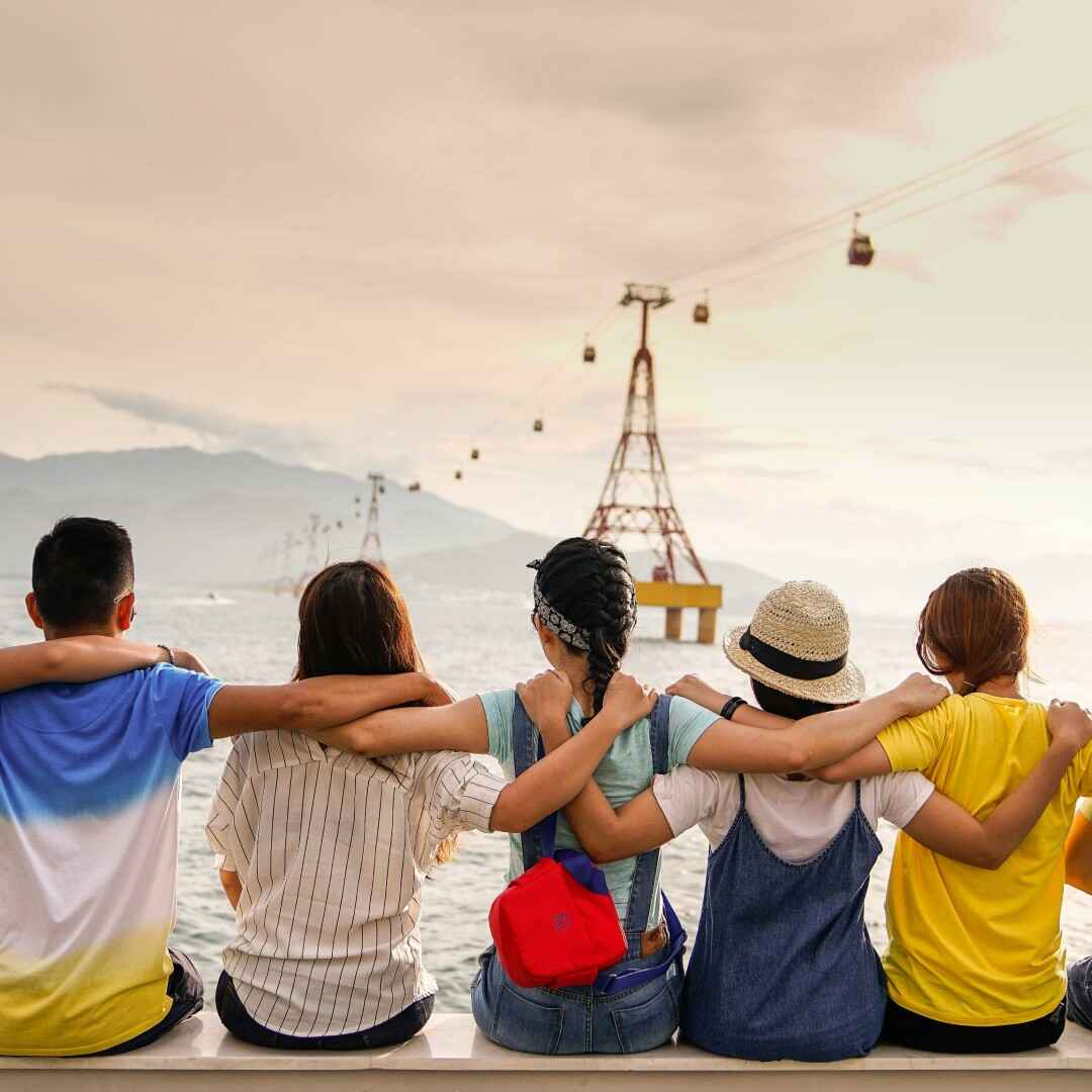 A group of friends sitting in a row with their arms around each other